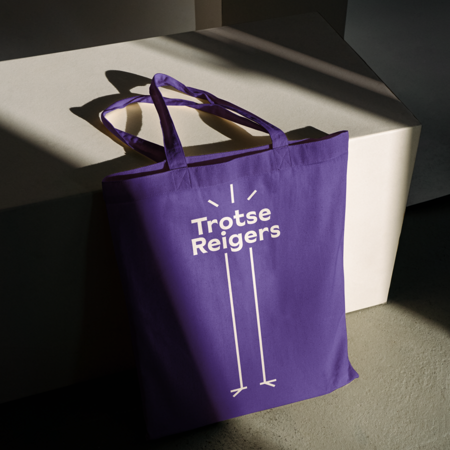 Een paarse totebag met Trotse Reigers er op, die leunt tegen een blok